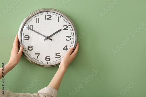 Young woman hanging clock o...