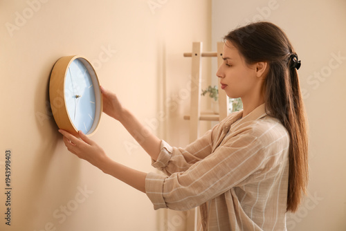 Young woman hanging clock o...