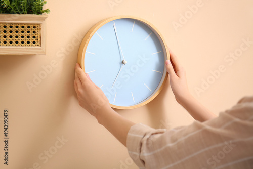 Young woman hanging clock o...