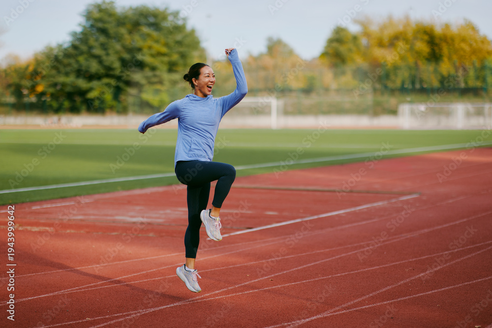 Obraz premium Excited young asian woman jumping with joy after outdoor workout