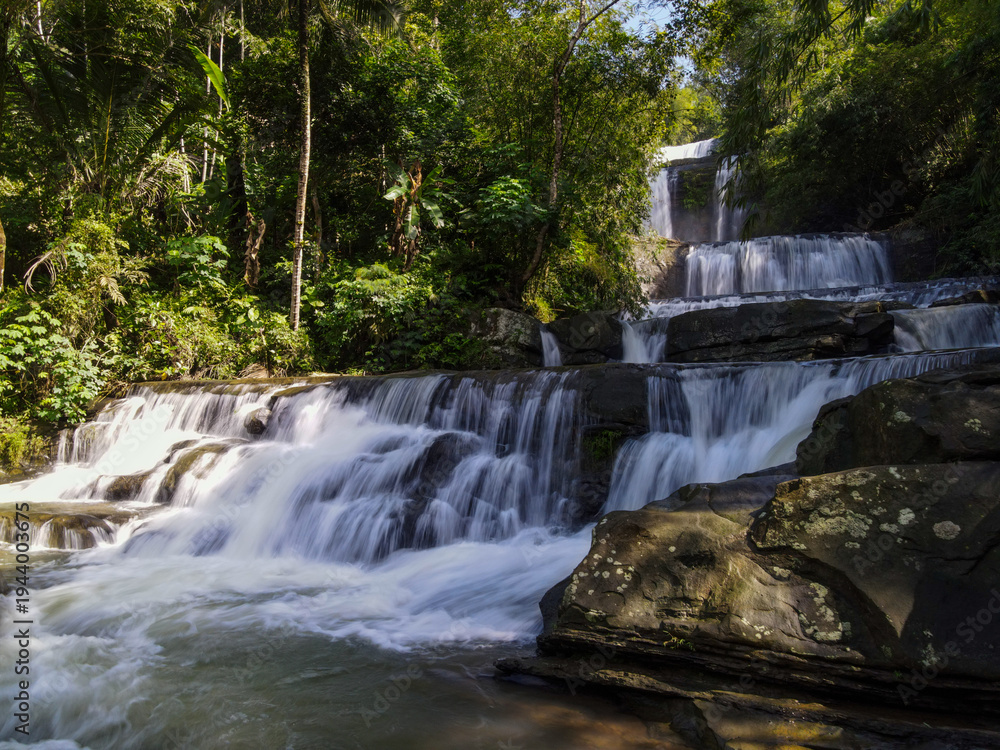 Fototapeta premium Epic Aerial View of Nangga Tiered Waterfall in Tropical Forest, Central Java Indonesia. Long Exposure Drone Shot 