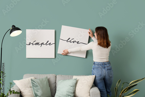 Young woman hanging picture...