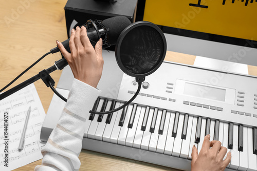 Obraz na płótnie Female hands with microphone playing synthesizer on table in recording studio, c
