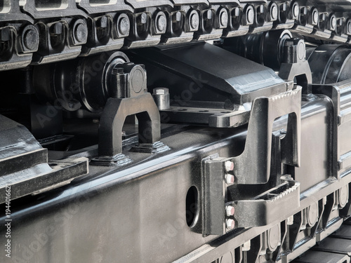 Close view of a tracked vehicle showing its undercarriage and suspension parts in a machinery workshop during daylight