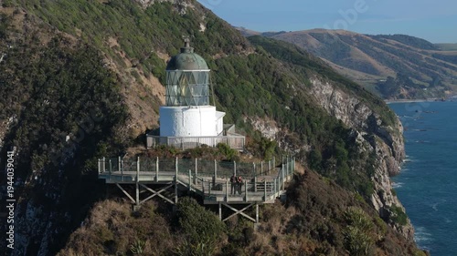 Tourists visiting Nugget Point lighthouse viewpoint on coastal cliffs in Otago New Zealand aerial view