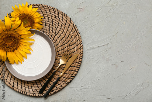 Foto Beautiful table setting with golden cutlery and sunflowers on grey background