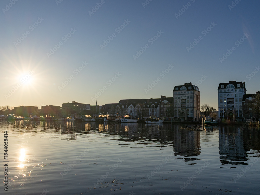 Fototapeta premium Turnhout, Antwep, Belgium, March 1st, 2026, Sunset reflection on waterfront with modern apartments and boats in Turnhout, Belgium
