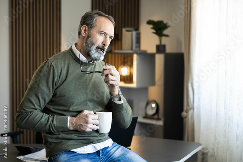 Foto Thoughtful businessman with grey beard and green sweater pondering a new idea in