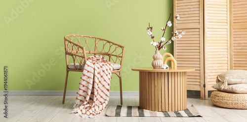 Interior of stylish living room with armchair and cotton flowers on wooden coffee table