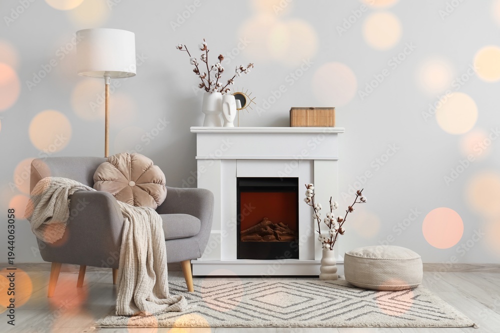 Obraz premium Grey armchair, fireplace and vases with cotton flowers near white wall in interior of living room