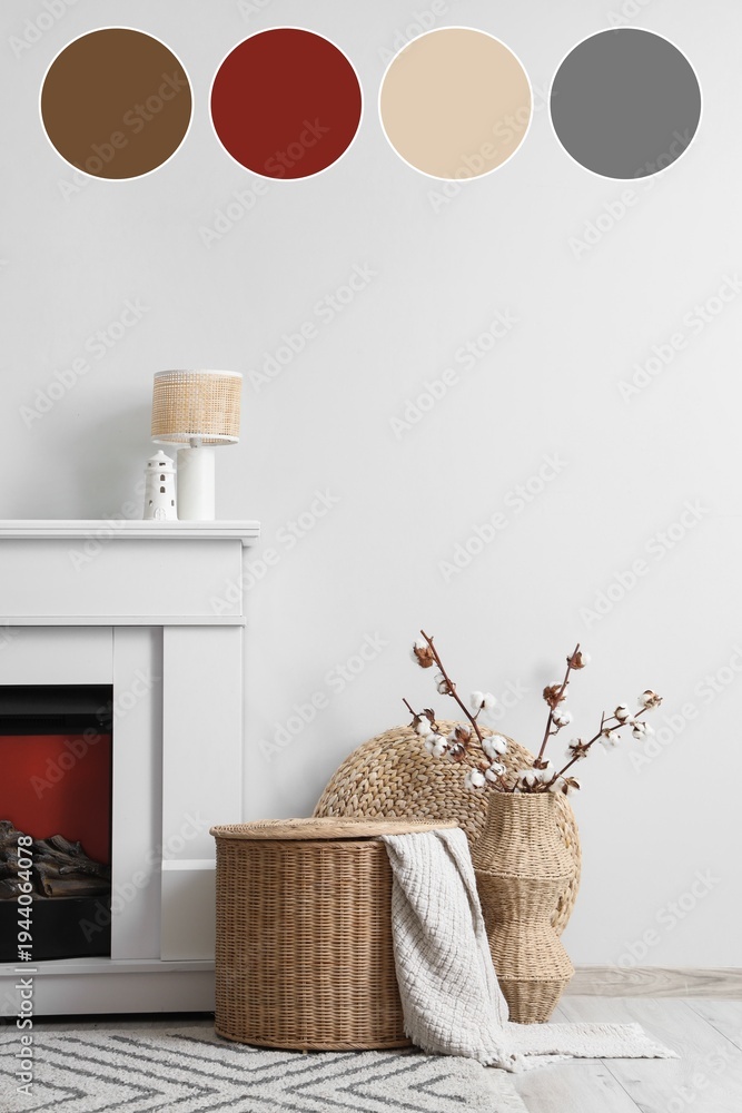 Naklejka premium Fireplace, wicker basket and vase with cotton flowers near white wall in interior of living room. Different color patterns