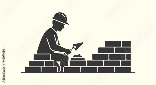 Silhouette of a construction worker building a brick wall.