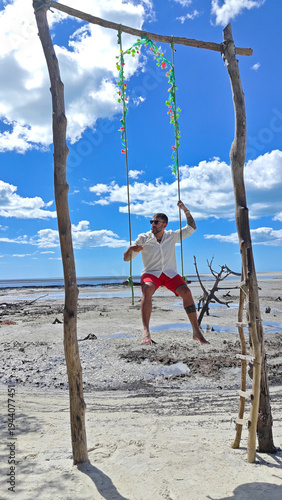 Man Sitting on a Wooden Swing at Jericoacoara Beach in Ceara, Brazil