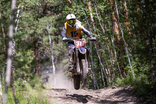 Off-road dirt bike rider speeding through forest trail