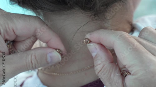 Woman necklace fasten close up of a woman fastening a delicate gold chain necklace around her neck getting ready for the day