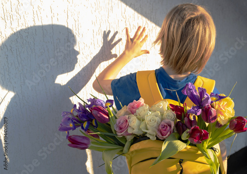boy with bright yellow backpack full of colorful spring flowers. child plays with shadow on wall. little courier, loving gift for mom. The awakening of nature. A time for joyful walks in nature