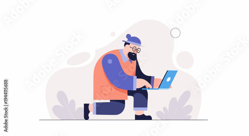 Man wearing hat and glasses, kneeling and working on a laptop
