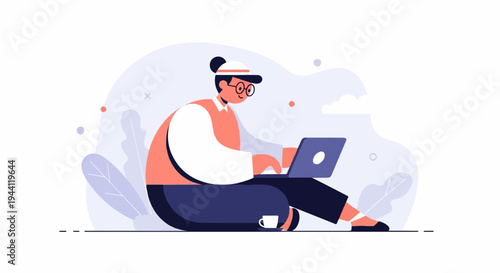 Person in glasses and cap sits cross-legged with laptop, cup nearby