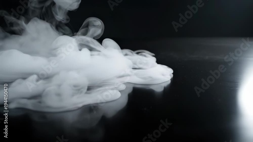 White thick smoke vapor flowing slowly across reflective black surface in low key studio lighting, for abstract mystery, chemical reaction, atmospheric effect