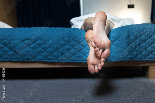 Fotografi Woman's bare feet dangling over the edge of a bed in a hotel room