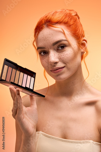 Foto Stylish young woman showcasing a stunning makeup palette with vibrant backdrop