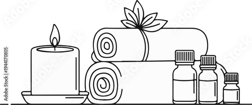 Still life of spa items lit candle, rolled towels, and small bottles