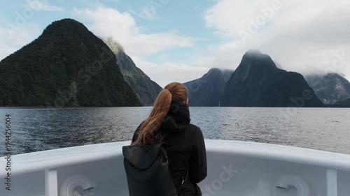Traveler on boat cruising through Milford Sound fjord surrounded by dramatic mountains, Fiordland National Park, New Zealand