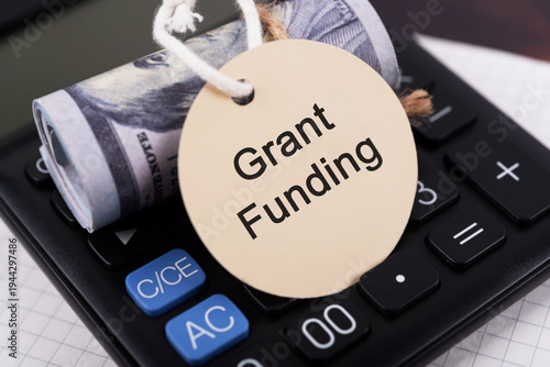 Grant funding text on a round paper note with money roll and calculator