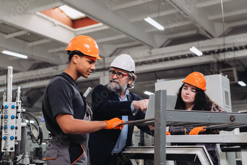 Tableau sur toile Experienced engineer guiding young manufacturing apprentices in factory