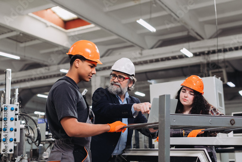 Bild auf Leinwand Mentor instructing young factory workers in manufacturing process