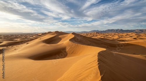 Vast Golden Sand Dunes Under Blue Sky with Clouds at Golden Hour in Desert Landscape