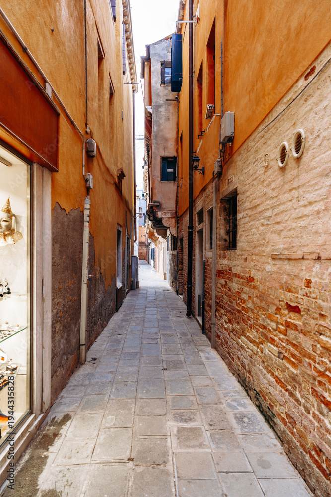 Naklejka premium Narrow walkway between buildings in a historic area with shops and stone pathways