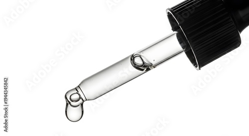 A close-up view of a dropper releasing a single drop of clear liquid