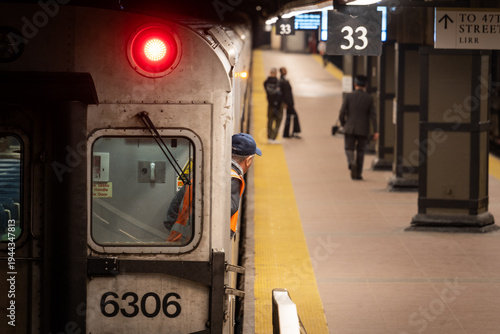 Sur un quai de gare un conducteur de train contrôle le quai avec trois passager à New-York