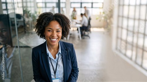 Portrait of a smiling black businesswoman in a modern office. Confident female executive wearing a suit and ID badge. Corporate career and diversity concept