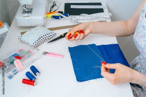 Close-up of hand basting stitch on blue fabric pieces in dressmaking process