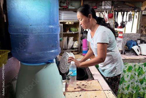 Middle-aged Filipino woman washing kitchen utensils in authentic rustic home kitchen, Asian lady doing domestic chores, daily life routine portrait