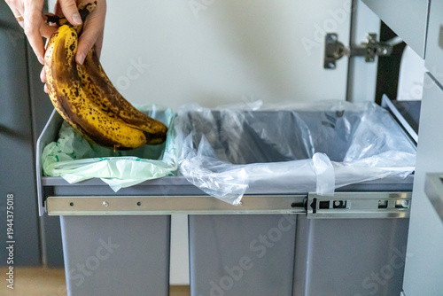 Quadro su tela A housewife throwing tainted bananas into a garbage bin in kitchen