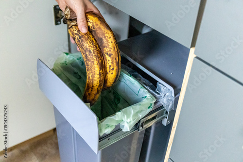 Photography A housewife throwing tainted bananas into a garbage bin in kitchen