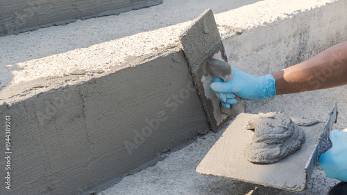 Hand worker plastering with holding trowel handle polished wet grey cement baton craft mix Plaster texture stair wall concrete Background well free space for text presentation construction house site 