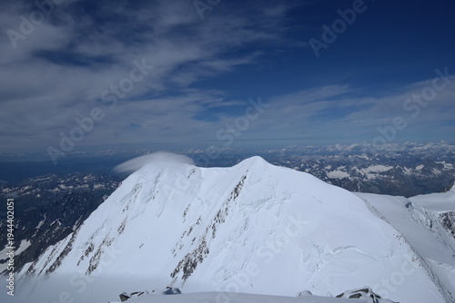 Tranquil Lake With Lush Green Forest, Snow-Capped Mountain, Blue Sky And White Clouds