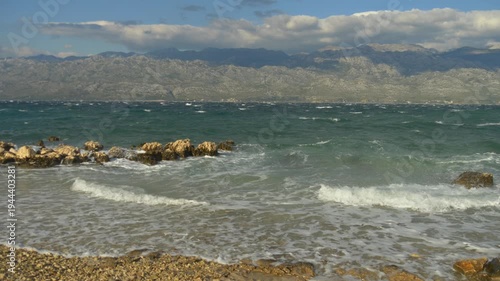 Sea waves crashing on rocky Adriatic coast with Croatian mountains in background