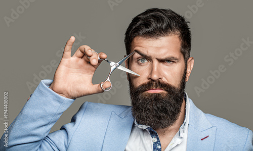 Mans haircut in barber shop. Barber scissors, barber shop. Brutal man, moustache. Male in barbershop, haircut, shaving. Bearded man isolated on gray background