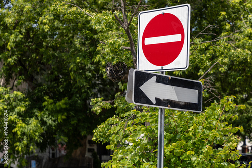 Do not enter and one way traffic sign on street. Red circle prohibited entry sign with arrow.