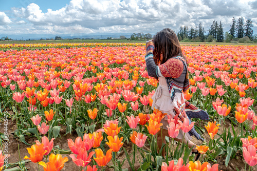 A woman is walking through a field of flowers