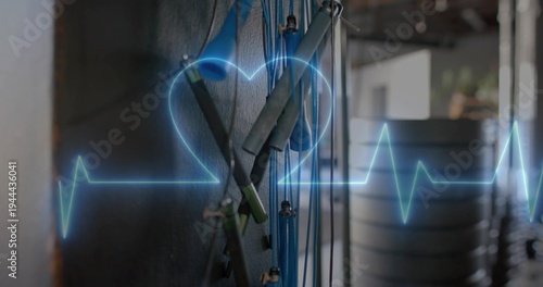 Displaying blue exercise cords with grey foam handles hanging on dark gym wall, neon EKG overlay