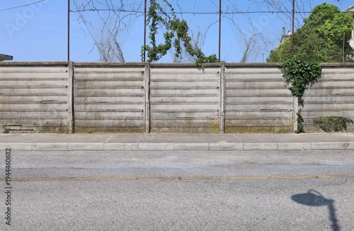 Wallpaper Mural Grunge prefab concrete wall with a broken protection metal net on top. Sidewalk and street in front. Background for copy space. Torontodigital.ca