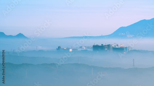 A scenic view of the urban landscape in New Taipei City, Taiwan, partially obscured by morning mist and clouds, viewed from Datong Mountain.