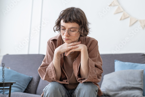 Quadro su tela Depressed teen girl sadly sits on sofa at home