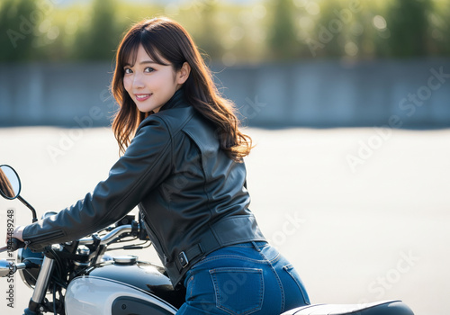 夕暮れ時の柔らかな光の中で、白いタンクのバイクに跨り振り返るレザージャケット姿の女性